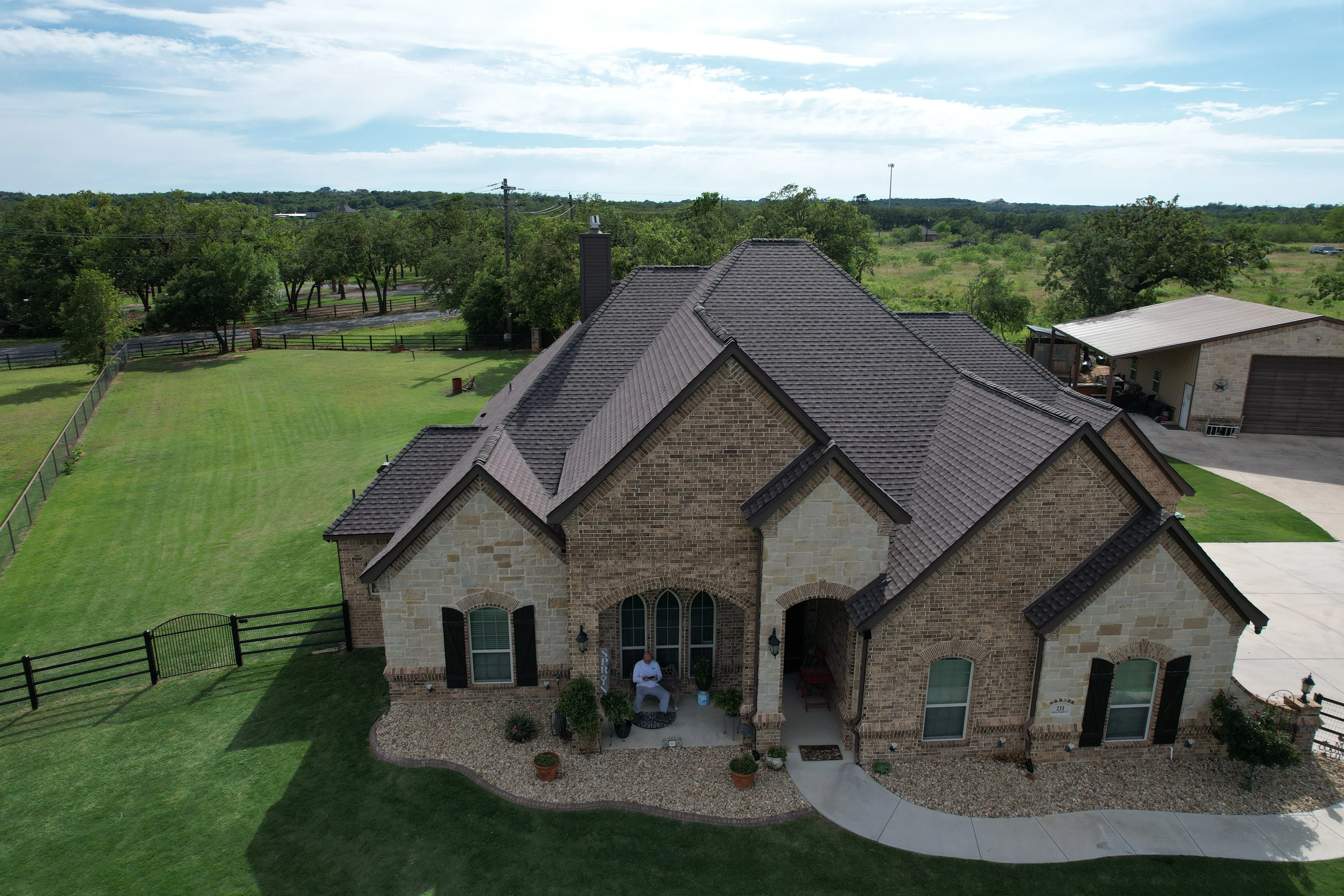 Charcoal gray dimensional shingle roof on multi-gabled brick and stone home with complex roofline