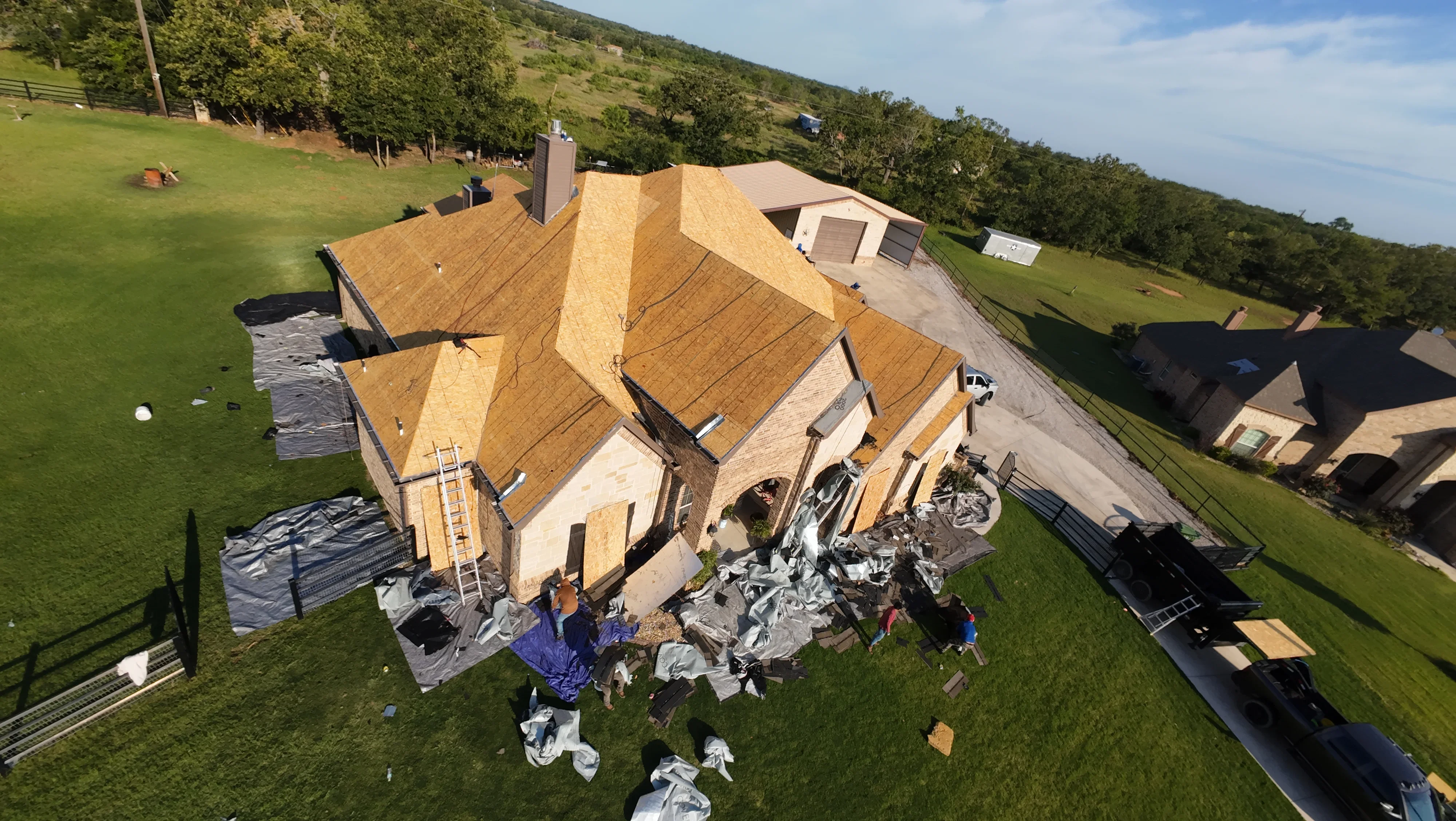 Aerial view of new wood shingle roof installation on multi-peaked residential home with chimney