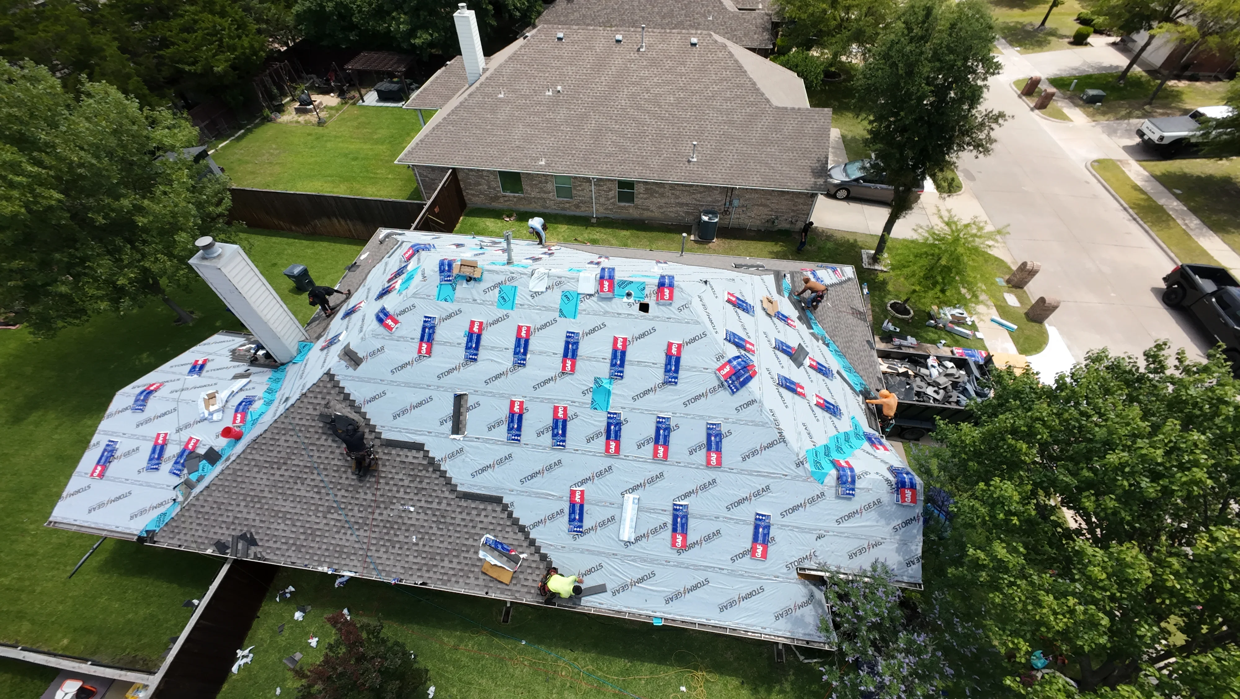 Aerial view of residential roof replacement with gray architectural shingles, underlayment, and ice-and-water shield installation