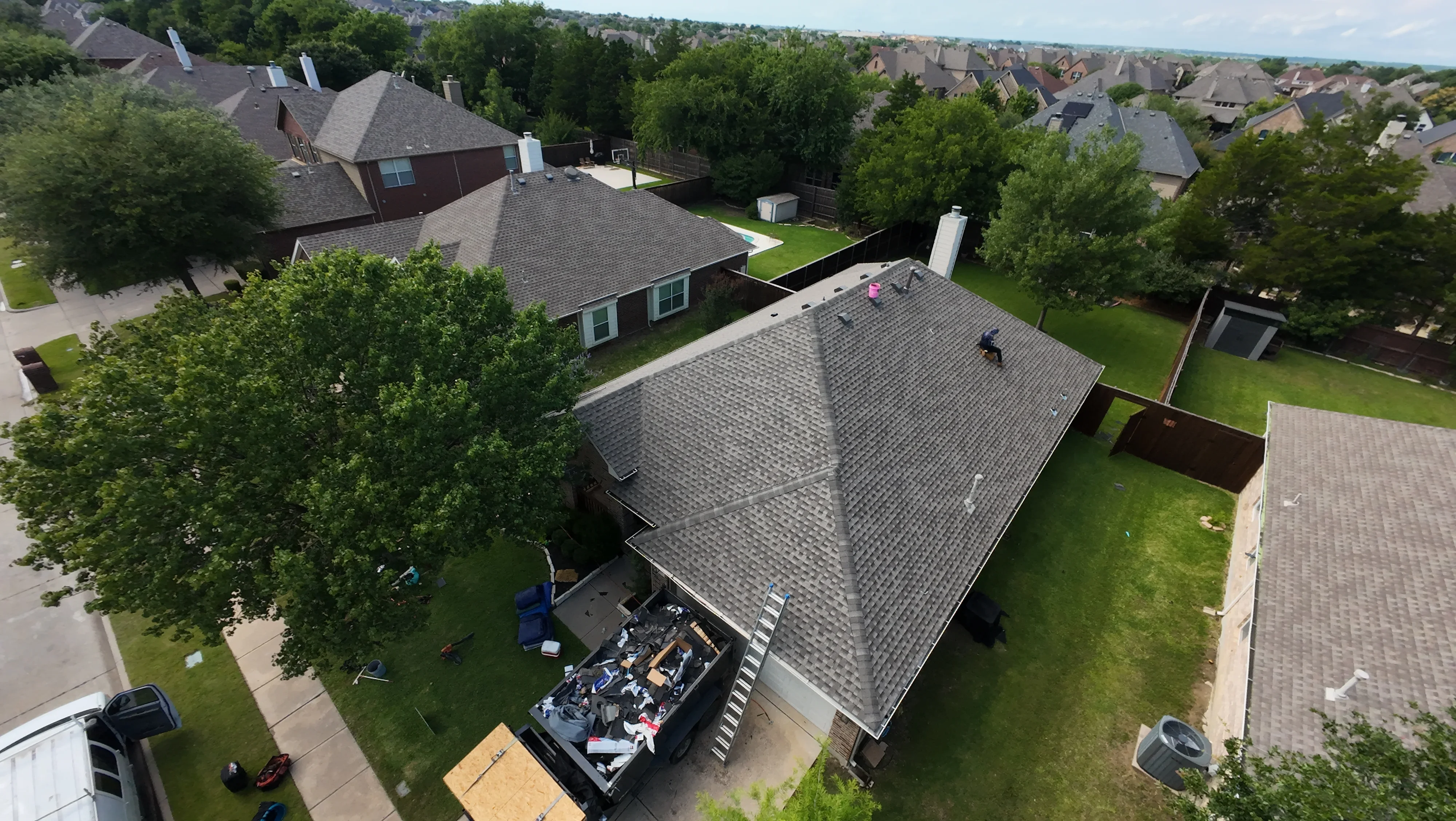 Aerial view of newly installed charcoal gray asphalt shingle roof on residential home