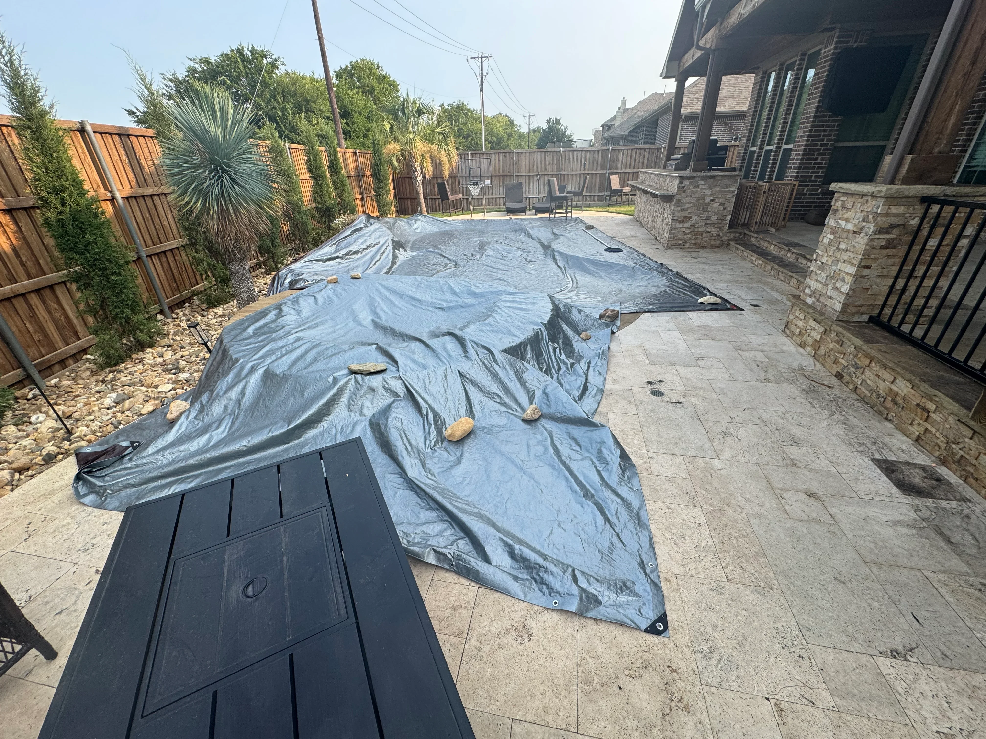 Blue EPDM pond liner installed in backyard with stone edging and landscaping